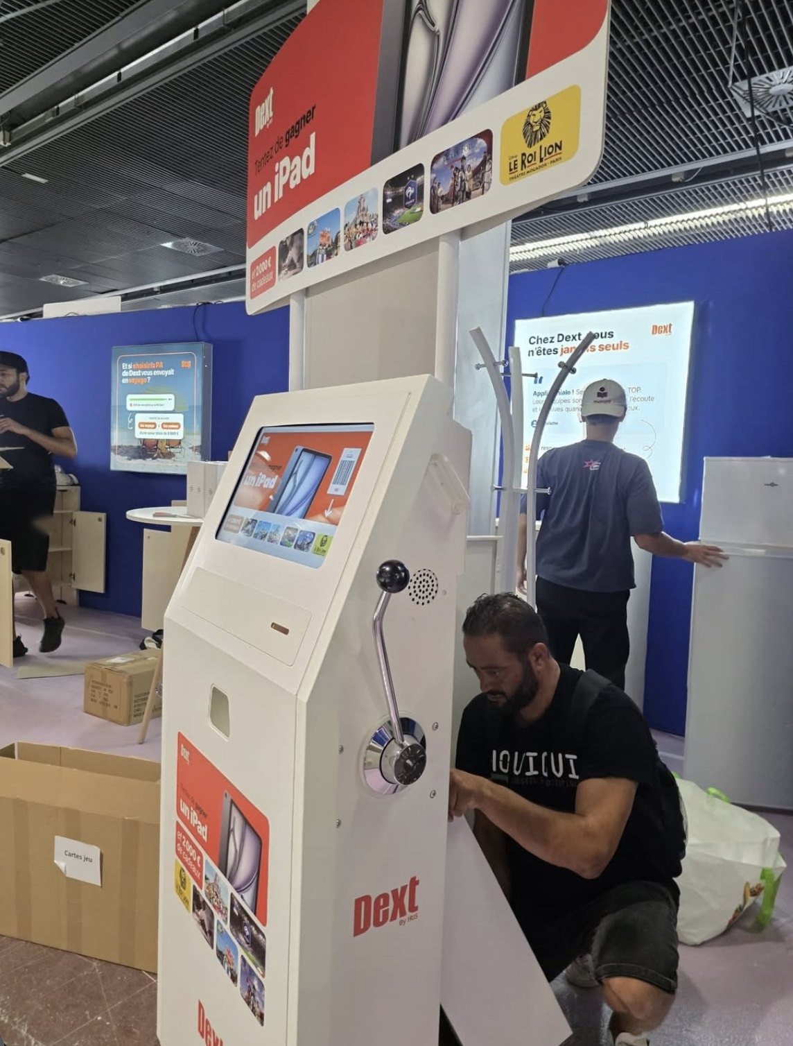 Un membre de l’équipe Chouigui installe une borne sur un stand de salon